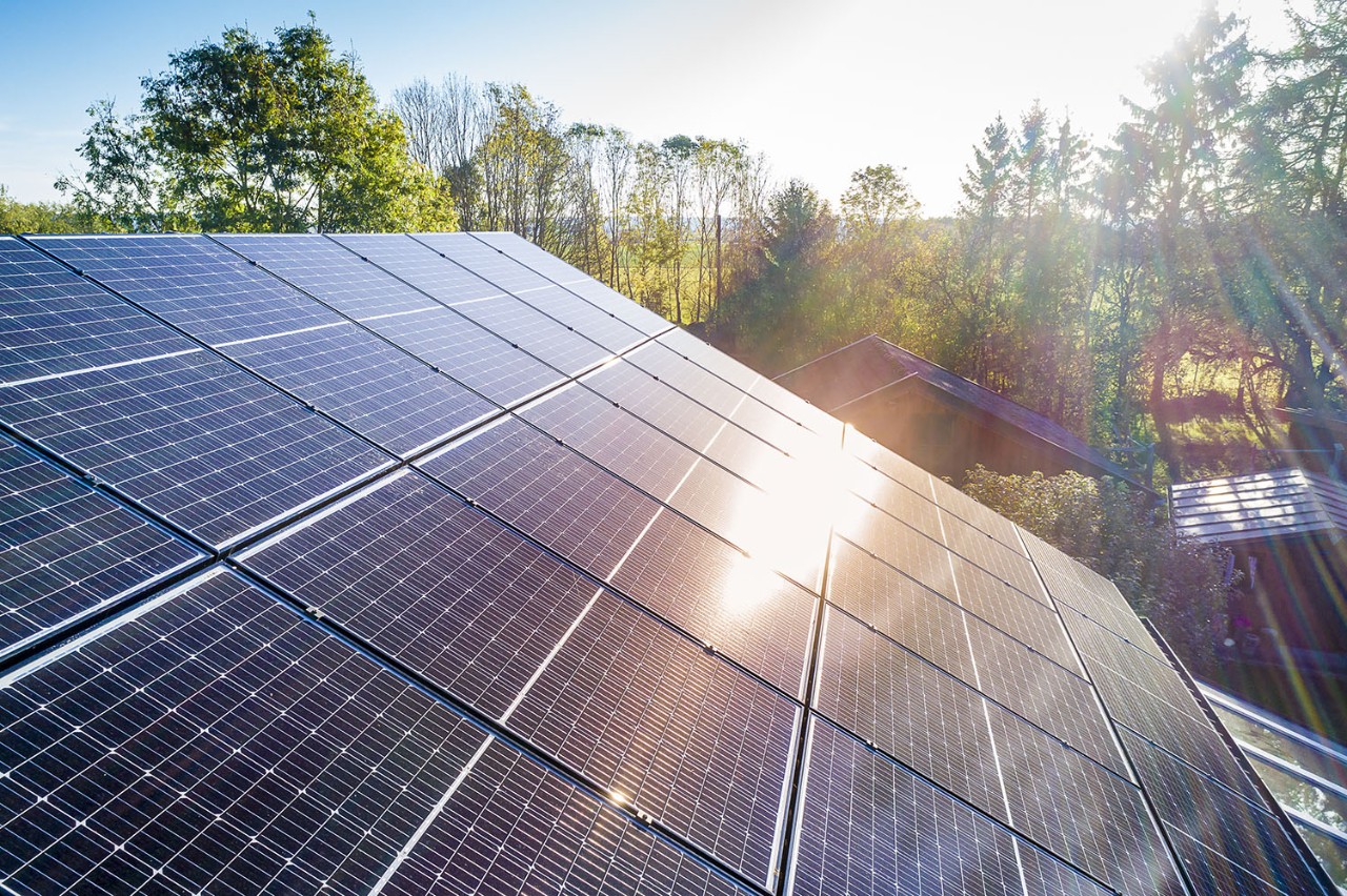 Solar panels and sunlight reflections on the roof against blue sky background. Concept clean power energy. Solar panels and sunlight reflextions on the roof against blue sky background. Concept clean power energy.