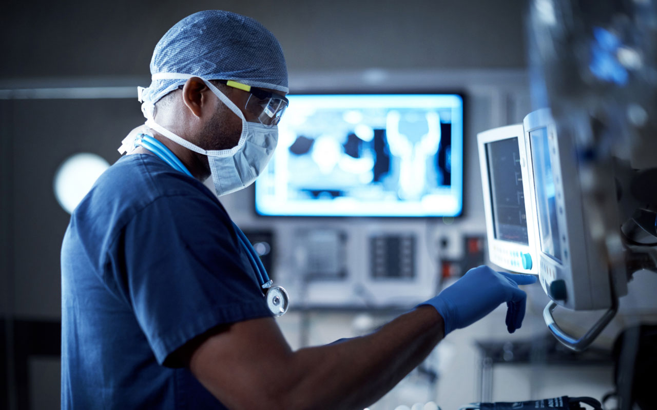 Doctor in surgical scrubs reading a monitor